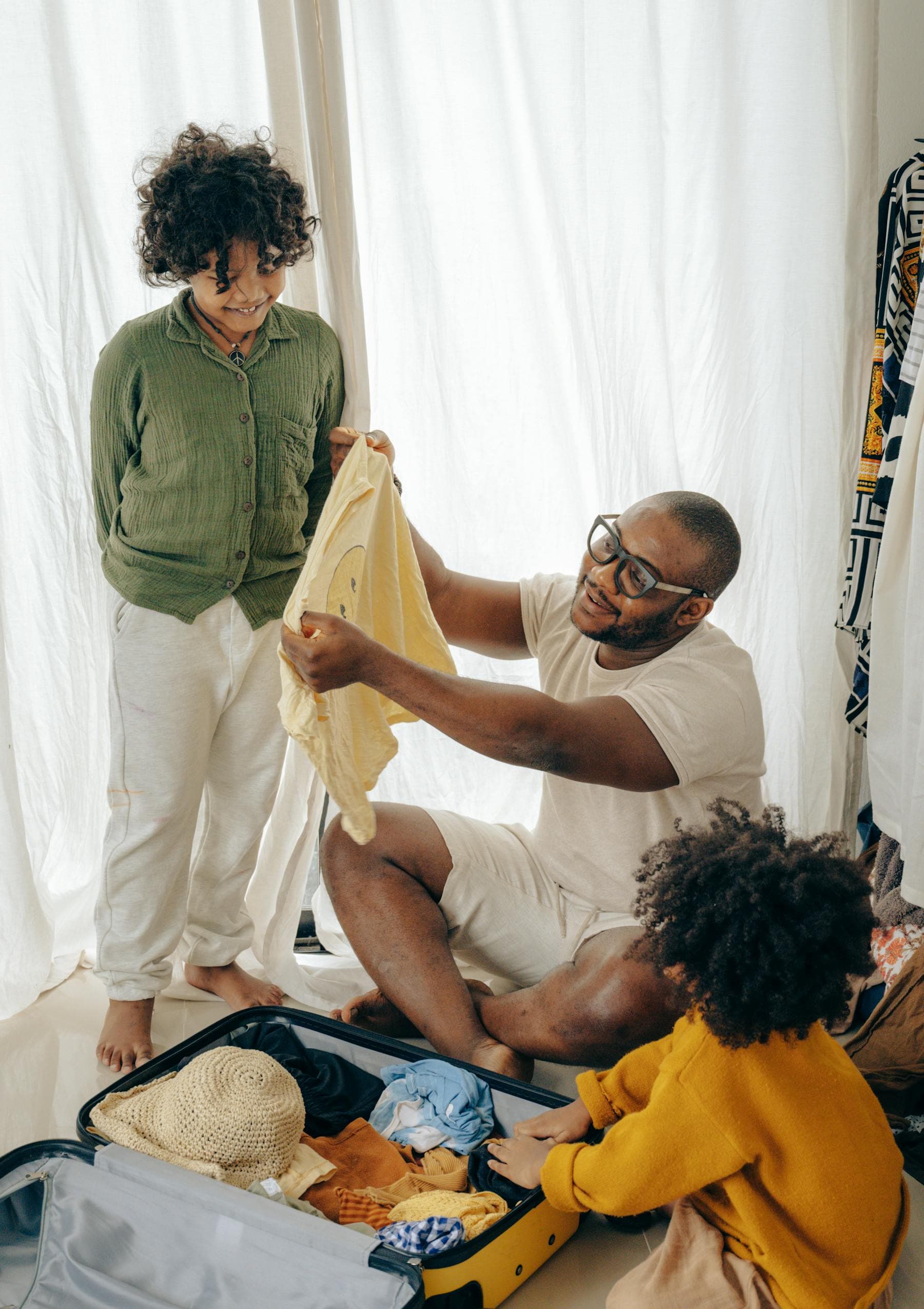 Father and children packing a suitcase at home before a family trip